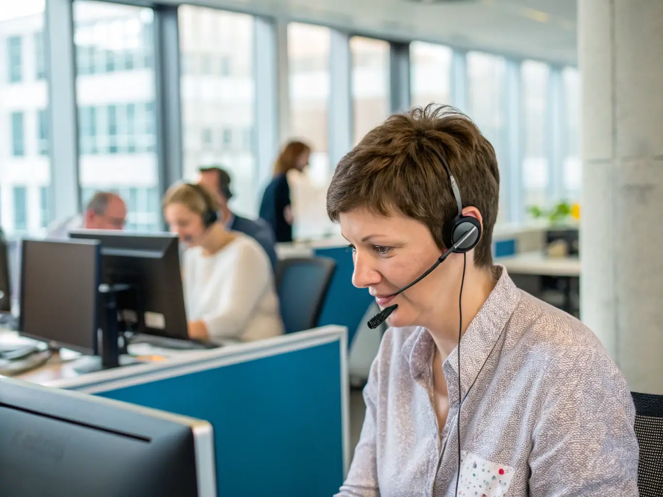 A close-up shot of a frustrated office worker holding a phone to their ear, with a blurred background of a busy office environment, symbolizing call quality issues.